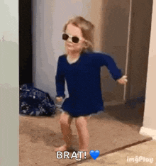 a little girl is wearing sunglasses and dancing in a room .