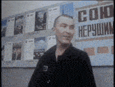 a man stands in front of a sign that says ' soko hepyshim '