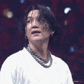 a close up of a person wearing a white shirt and a necklace