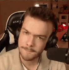 a man wearing headphones is sitting in front of a microphone in a chair .