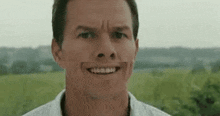 a close up of a man making a funny face while standing in front of a field .