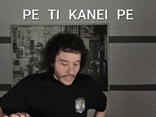 a man wearing a black shirt with the words pe ti kanei pe on the bottom