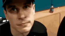 a man wearing a hat and a black shirt is making a face .