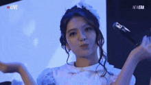 a woman in a white dress is standing in front of a microphone and blowing a kiss .