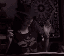 a woman wearing a hat and a t-shirt with a skull on it is smiling and waving
