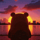 a teddy bear is looking at the sunset over a lake