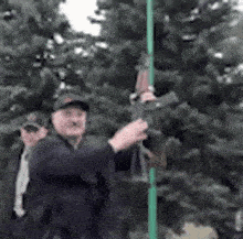a man is holding a gun while standing next to a green pole .
