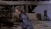 a man in a black leather jacket is standing in a room with a skeleton in the background