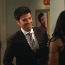 a man in a suit and tie smiles in front of a picture of another man