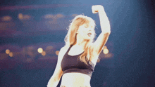 a woman in a black sports bra is flexing her arm