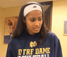 a woman wearing a headband and a hoodie that says notre dame on it