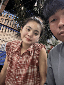 a man and a woman are posing for a picture and the woman is wearing a red plaid shirt