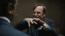 a man in a suit and tie is pointing at another man in a hallway