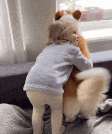 a little girl is hugging a stuffed dog while looking out a window