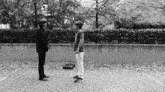 a black and white photo of two men standing next to each other on a brick sidewalk