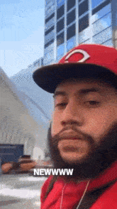a man with a beard wearing a red hat and a red hoodie says newwww
