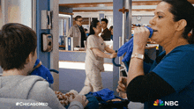 a nurse wipes her mouth with a blue towel while a child looks on