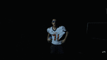 a blurry picture of a man wearing sunglasses and a white shirt that says ' nfl ' on it