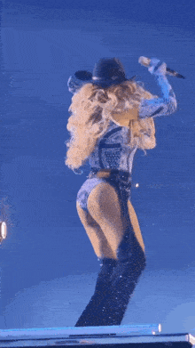 a woman wearing a cowboy hat and thigh high boots is dancing on a stage .