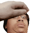 a hand is holding a man 's head and making a face .