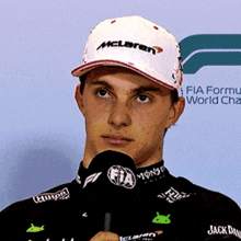 a man wearing a mclaren hat holds a microphone in his hand