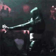 a woman in a green dress is singing into a microphone in a dark room .
