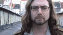 a man with long hair and glasses has a beard