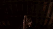 a man is hanging upside down in a dark room with a knife in his mouth .