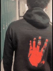 a man wearing a black hoodie with a red hand print on the back