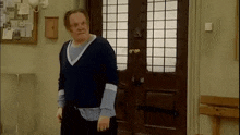 a man is standing in front of a wooden door in a room .