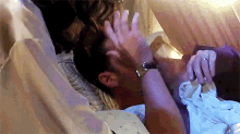 a man wearing a watch is laying in bed with a woman