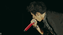 a man singing into a red microphone with the letter d visible in the corner