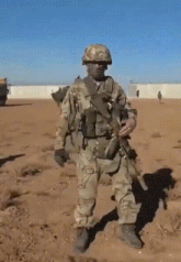 a soldier standing in the dirt with a gun