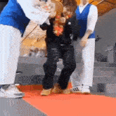 a group of people are standing next to each other on a red carpet and a person is walking on a red carpet .