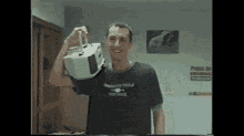 a man in a black shirt is holding a white box in his hand .