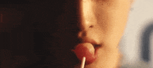 a woman is licking a lollipop in her mouth in a close up .