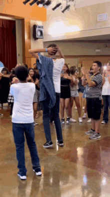 a group of people are dancing in a room with a speaker on the wall above them
