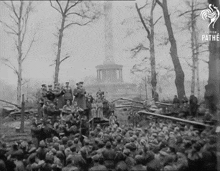 a group of people are gathered in front of a statue that says pathe on the bottom