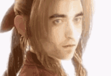 a close up of a man 's face with long hair and a red shirt .