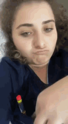 a woman with curly hair is making a funny face while holding a pen in her pocket .