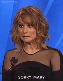 a woman in a black dress is standing in front of a microphone and making a face .