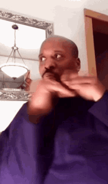a man in a purple shirt looks at himself in the mirror