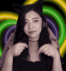 a woman wearing cat ears and a choker is standing in front of a colorful spiral .