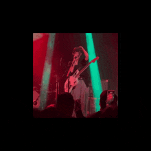 a woman playing a guitar and singing into a microphone