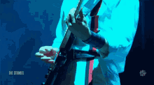 a man playing a guitar with the words the strokes on the bottom right