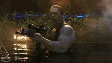 a man in a tank top is holding a gun in the water with a prime arrow in the background