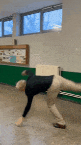a man is doing a handstand in a room with a bulletin board in the background