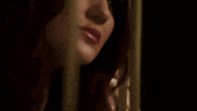 a close up of a woman 's face behind a curtain in a dark room .