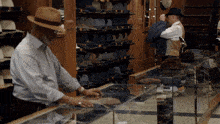 a man in a hat is looking at a hat on display in a store