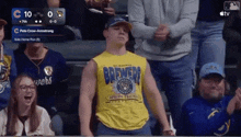 a man wearing a brewers shirt stands in the stands